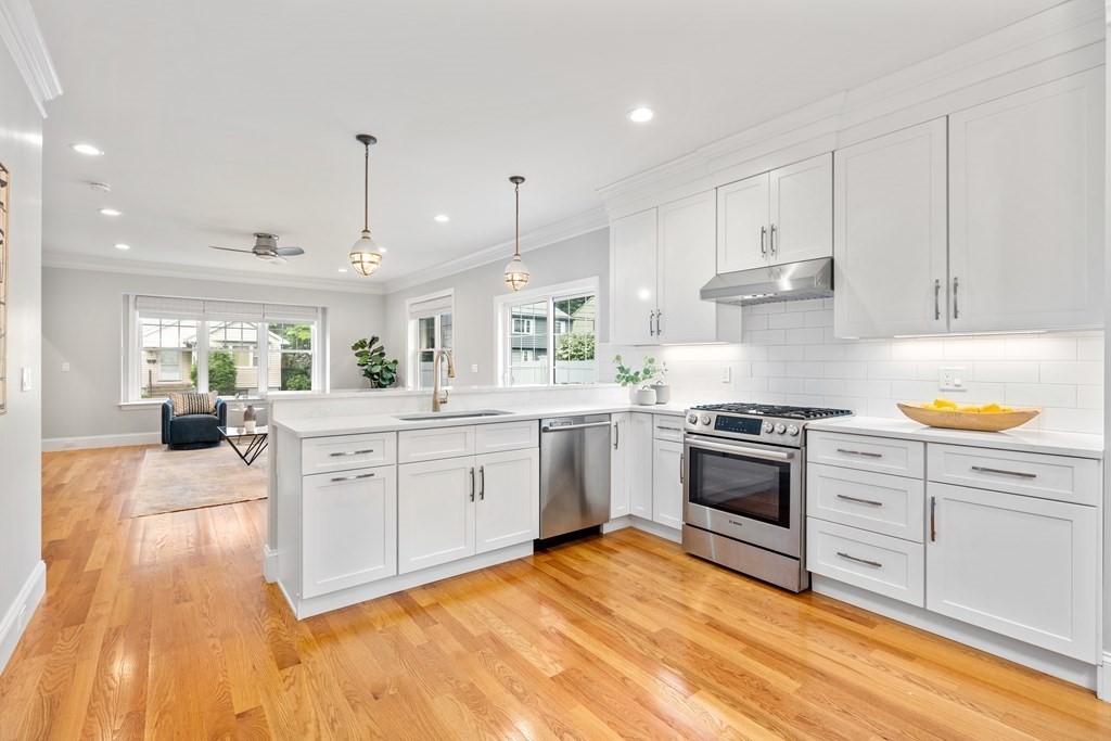 a large kitchen with stainless steel appliances granite countertop a stove a sink dishwasher and a oven with white cabinets