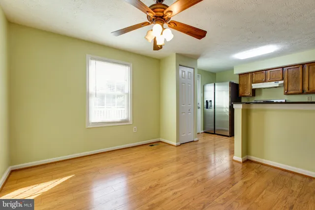 a view of a kitchen with a fridge a ceiling fan and wooden floor