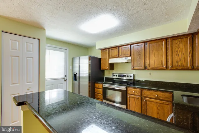 a kitchen with stainless steel appliances granite countertop a stove a refrigerator and a sink