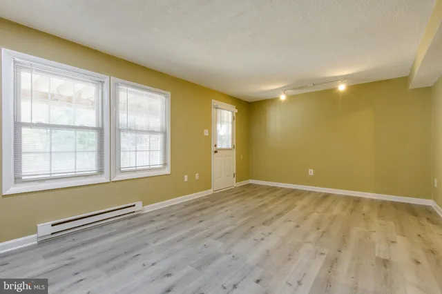 an empty room with wooden floor and windows
