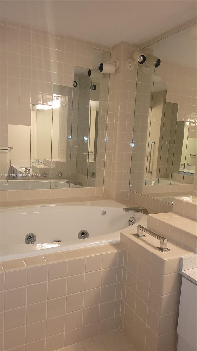 900 Northeast 195th Street, Unit 620 Miami, FL 33179 - Photo 16 of 28 a bathroom with a tub a sink and mirror