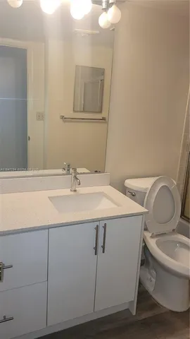 a bathroom with a granite countertop toilet sink and mirror