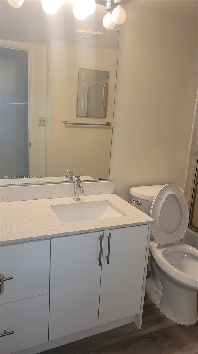 900 Northeast 195th Street, Unit 620 Miami, FL 33179 - Photo 22 of 28 a bathroom with a granite countertop toilet sink and mirror
