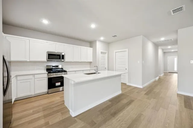 a kitchen with a refrigerator stove and white cabinets
