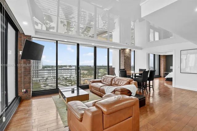 a living room with furniture tv and floor to ceiling windows