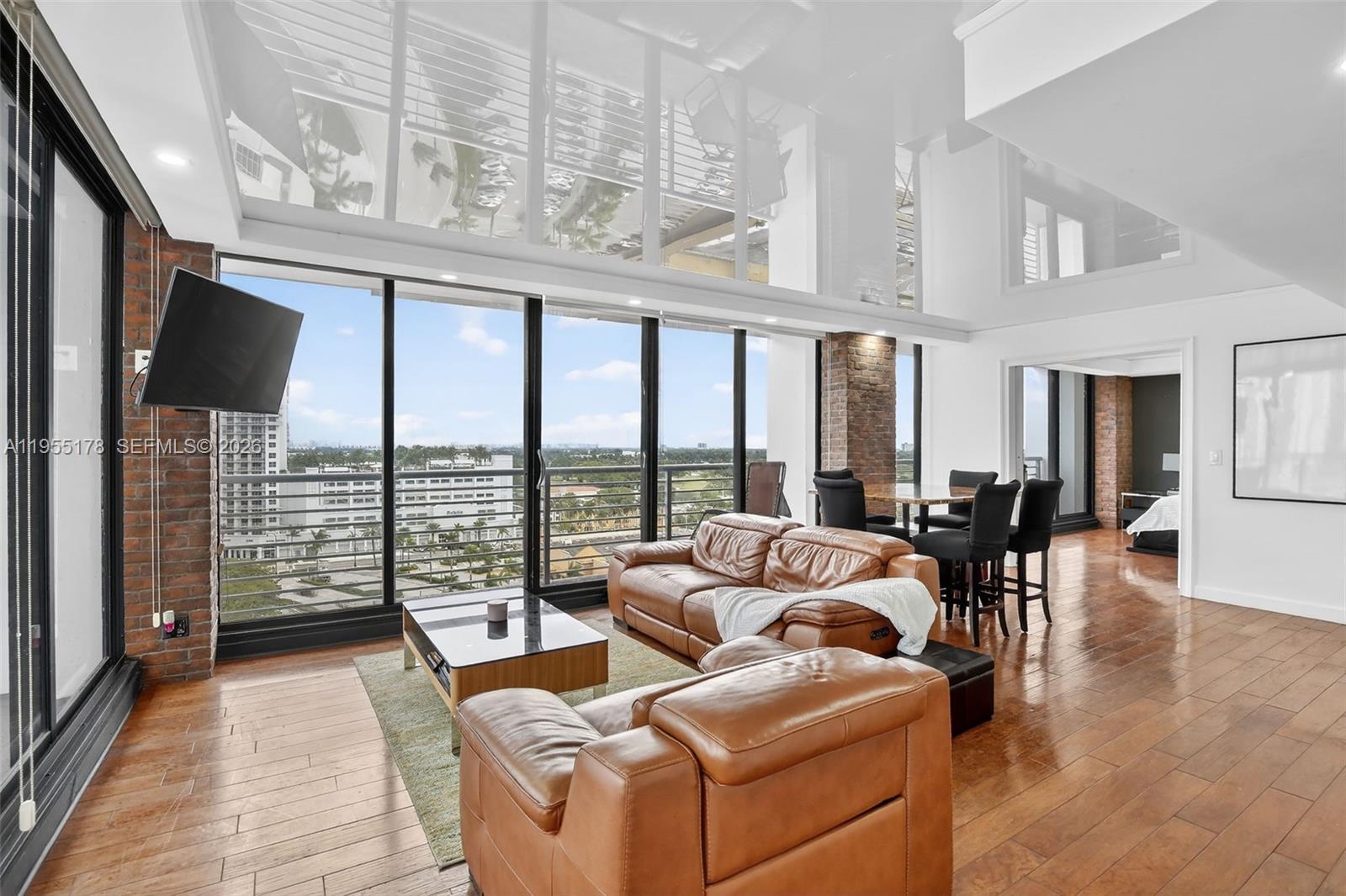 a living room with furniture tv and floor to ceiling windows