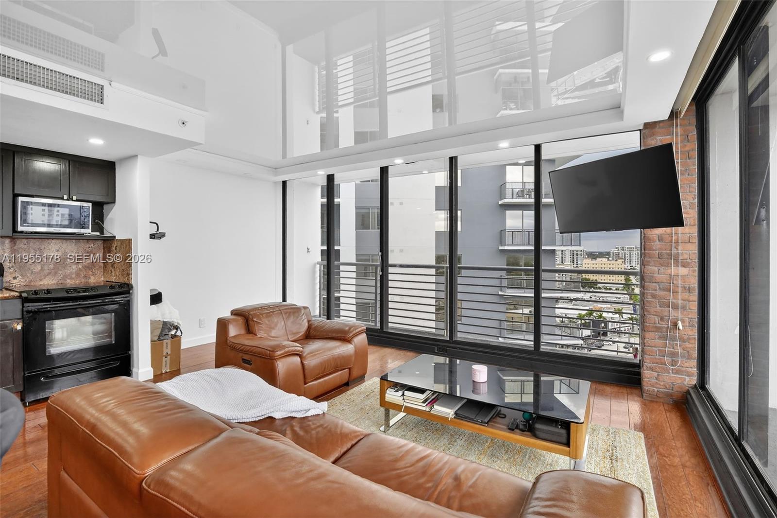 1720 Harrison Street, Unit 14H Hollywood, FL 33020 - Photo 12 of 37 a living room with furniture a flat screen tv and kitchen view