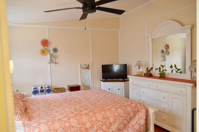 a bedroom with a bed a mirror on the dresser and a window