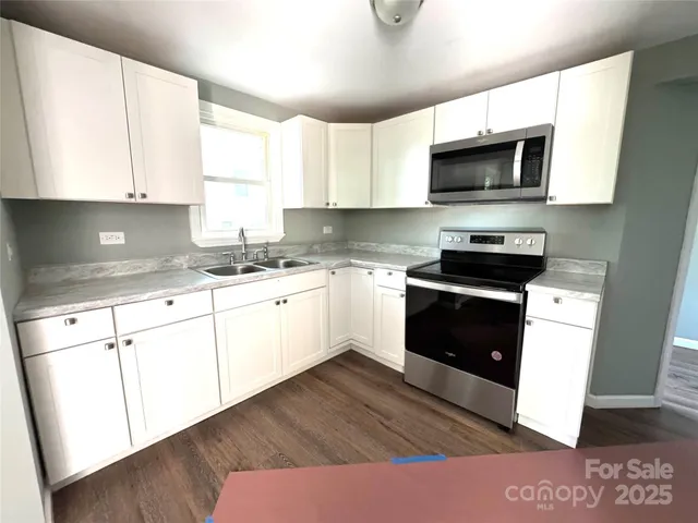 a kitchen with stainless steel appliances granite countertop a stove a sink and a microwave