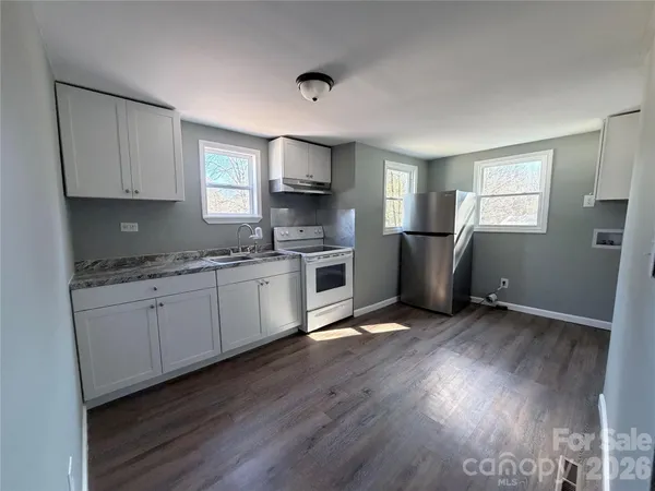 a kitchen with granite countertop a refrigerator stove top oven and sink