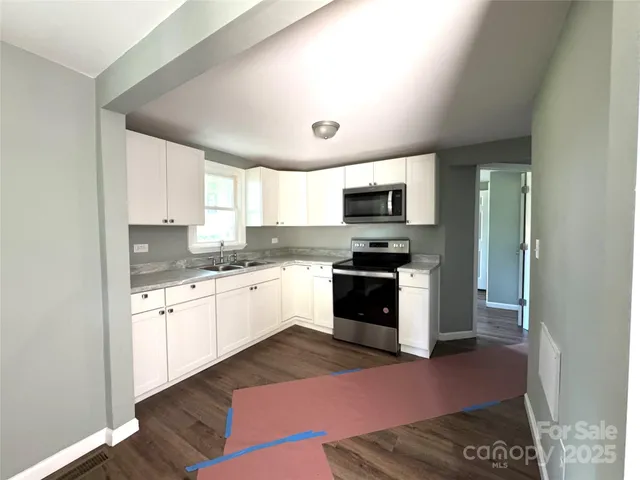 a kitchen with granite countertop a stove a sink and a microwave