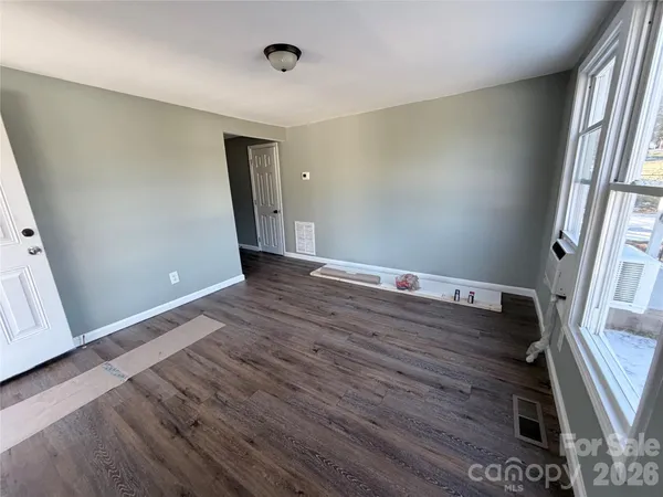 an empty room with wooden floor and windows