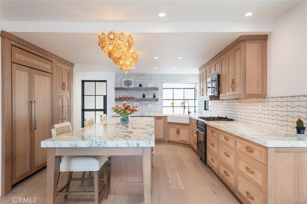 a kitchen with kitchen island granite countertop a table chairs a sink dishwasher window and cabinets