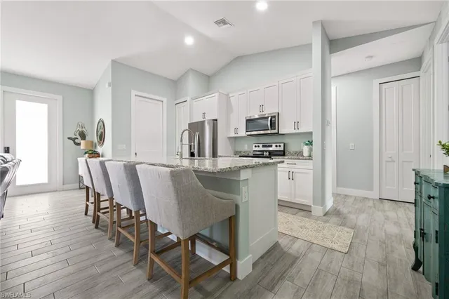 a kitchen with kitchen island granite countertop a center island stainless steel appliances cabinets and wooden floor
