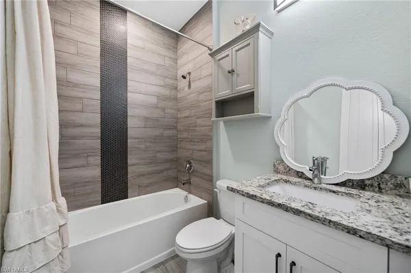 a bathroom with a granite countertop sink toilet and shower