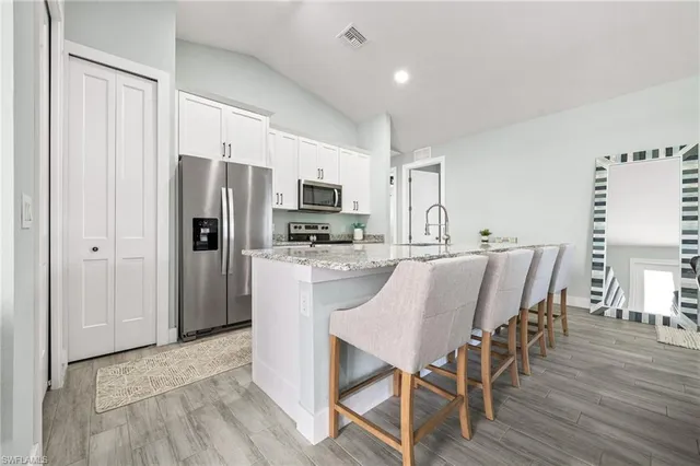 a kitchen with kitchen island white cabinets and stainless steel appliances