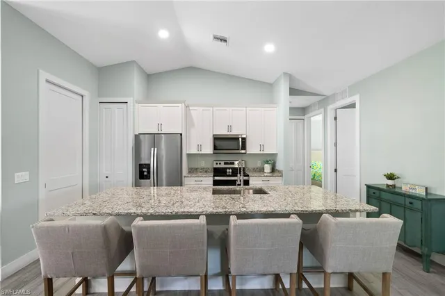 a kitchen with stainless steel appliances granite countertop a stove a sink a microwave a dining table and chairs