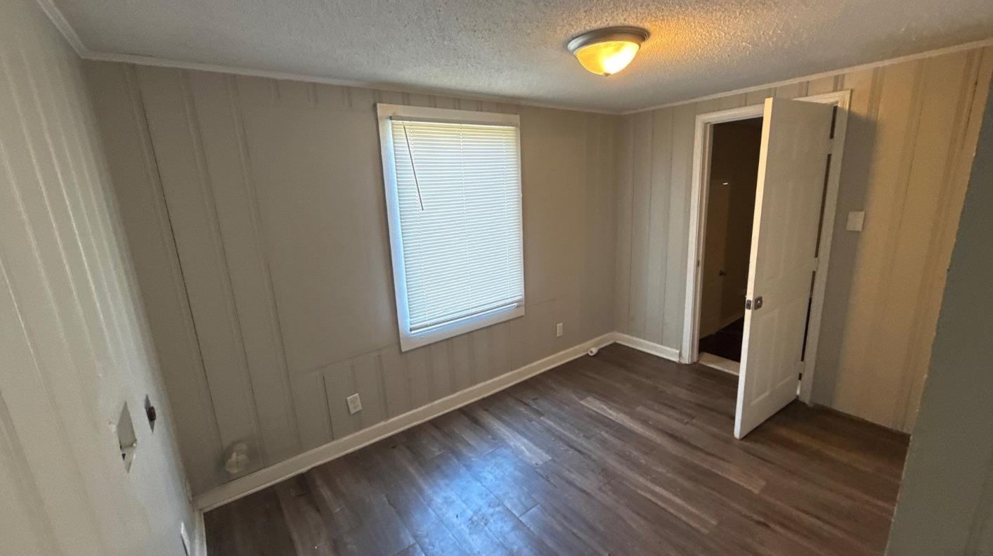 1311 Marlin Road Memphis, TN 38116 - Photo 4 of 4 Unfurnished bedroom featuring dark wood-style flooring and a textured ceiling
