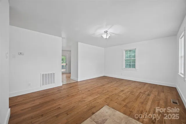 a view of an empty room with a window and wooden floor