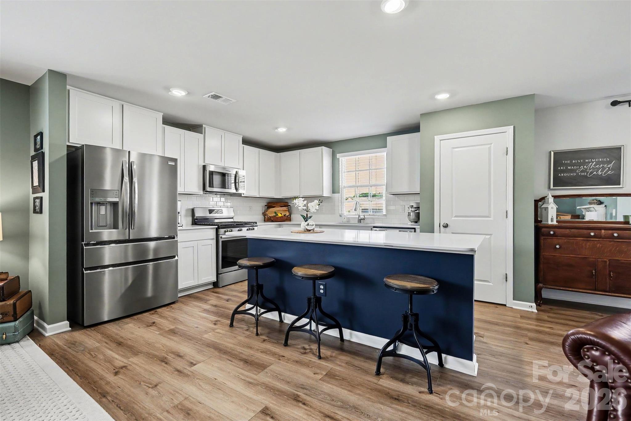 a kitchen with a refrigerator a dining table and chairs