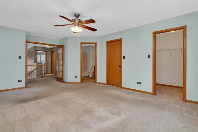 an empty room with ceiling fan and windows
