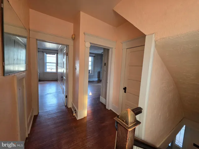 an empty room with wooden floor chandelier fan and windows