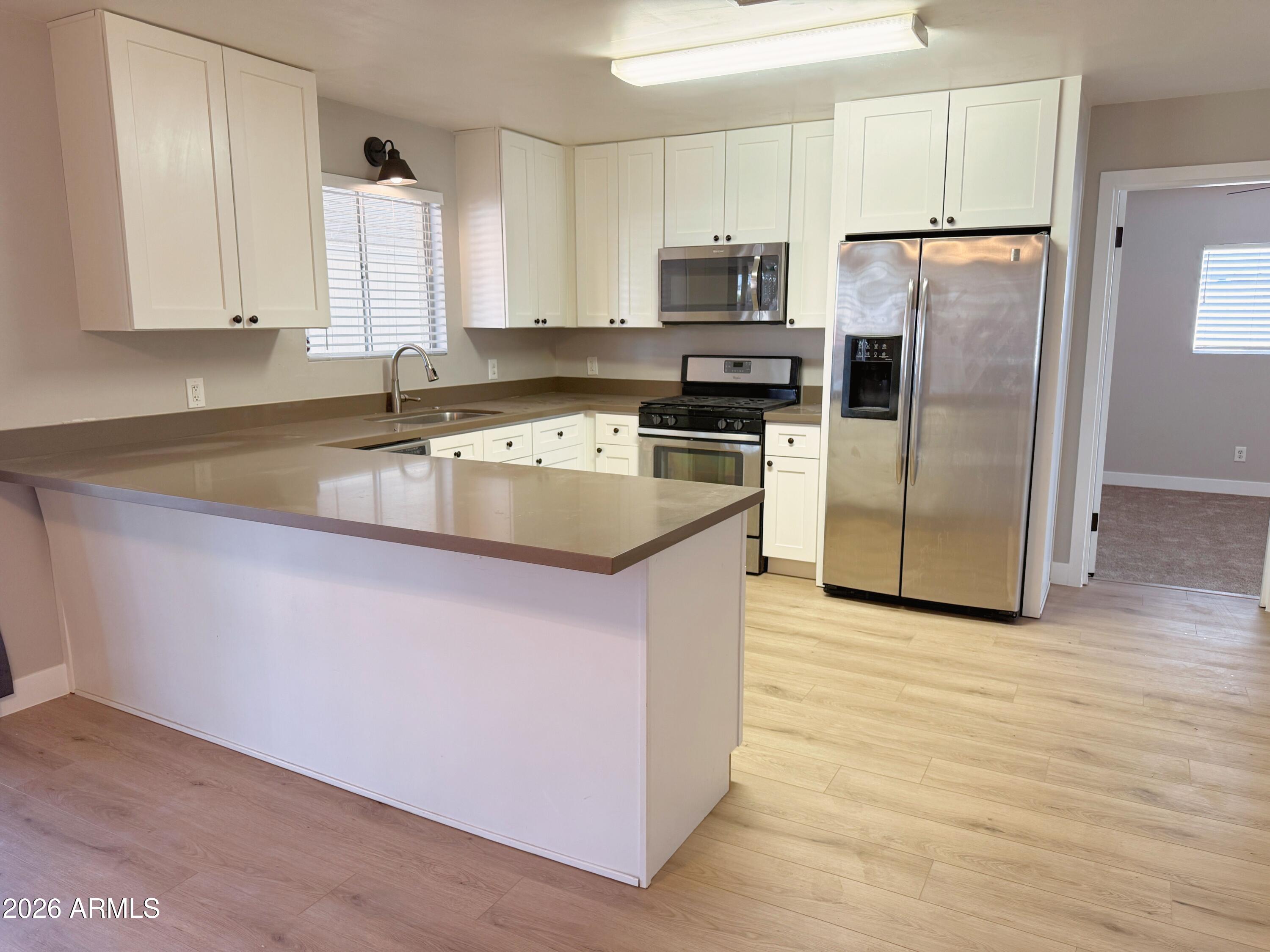 1220 West Romo Jones Street Tempe, AZ 85281 - Photo 7 of 26 a kitchen with stainless steel appliances granite countertop a refrigerator a stove a sink and white cabinets