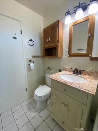 a bathroom with a granite countertop sink toilet and mirror