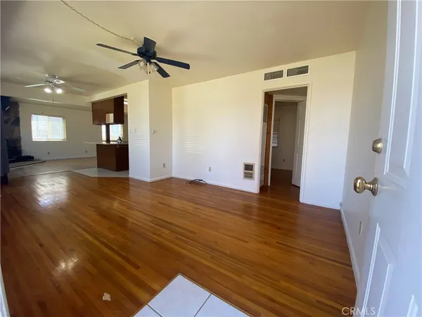 a view of a room with wooden floor and a ceiling fan