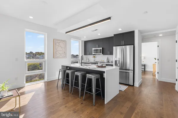 a kitchen with stainless steel appliances a dining table chairs refrigerator and microwave