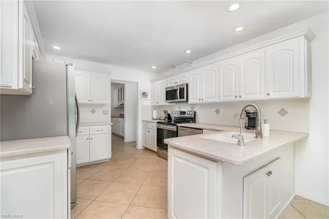 a kitchen with a sink a stove a refrigerator and white cabinets
