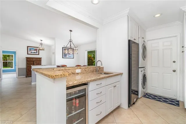 a hall with kitchen island granite countertop white cabinets and sink