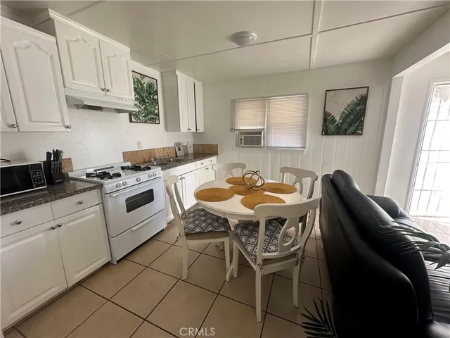 a kitchen with stainless steel appliances granite countertop a table chairs sink and cabinets