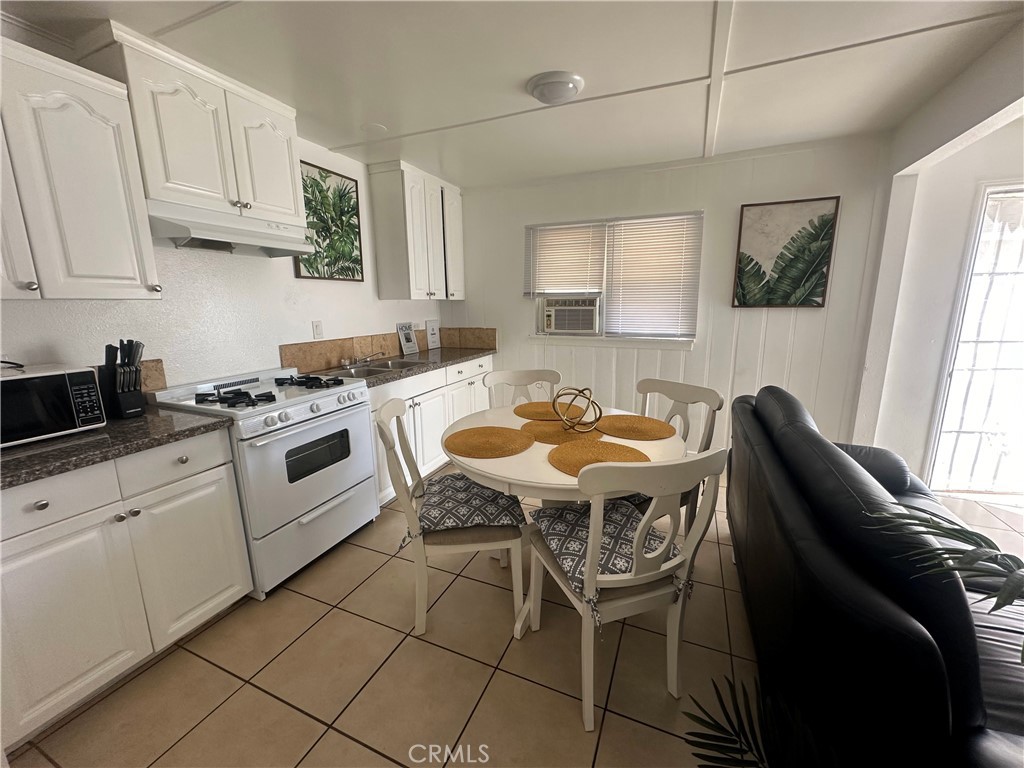 9723 Belmont Street, Unit 1/2 Bellflower, CA 90706 - Photo 2 of 7 a kitchen with stainless steel appliances granite countertop a table chairs sink and cabinets