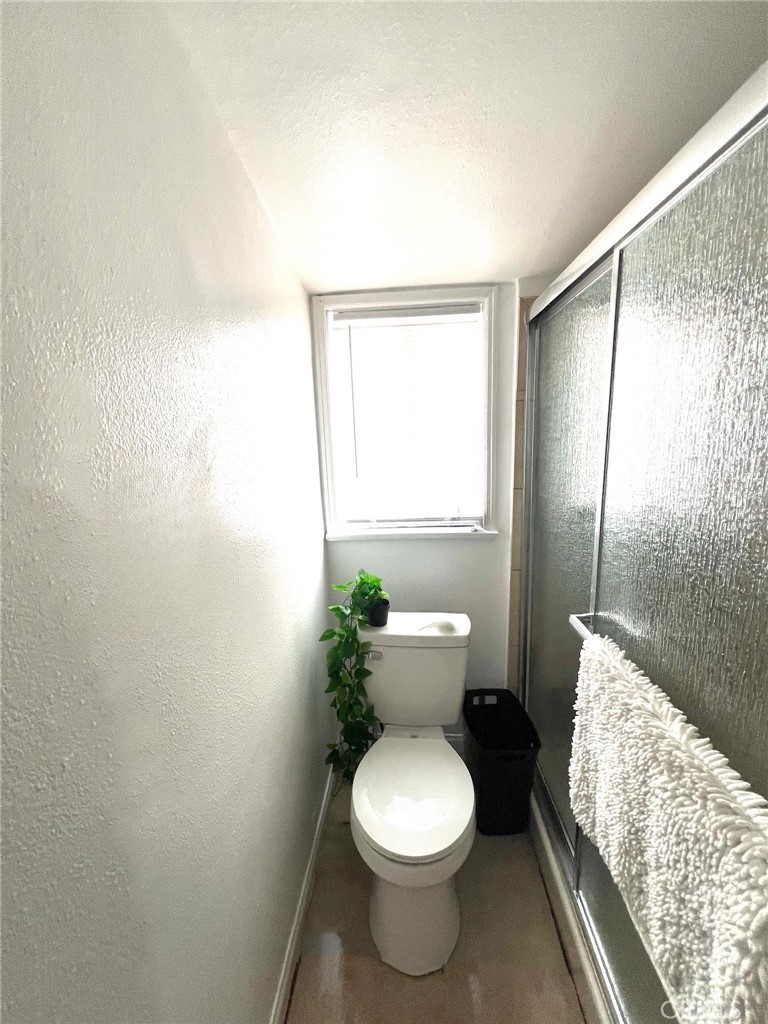 9723 Belmont Street, Unit 1/2 Bellflower, CA 90706 - Photo 3 of 7 a white toilet sitting next to a bathroom sink and a shower