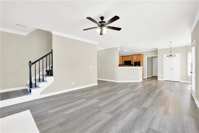 a view of an empty room with wooden floor and a ceiling fan