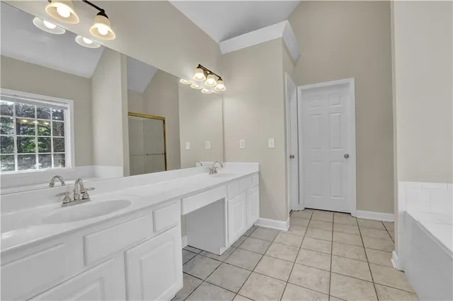 a spacious bathroom with a double vanity sink a mirror and a bathtub