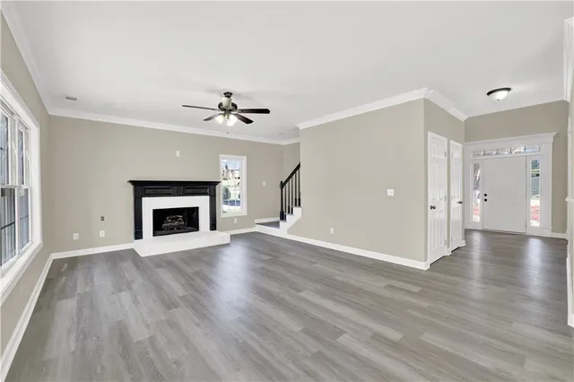 an empty room with wooden floor a fireplace and windows