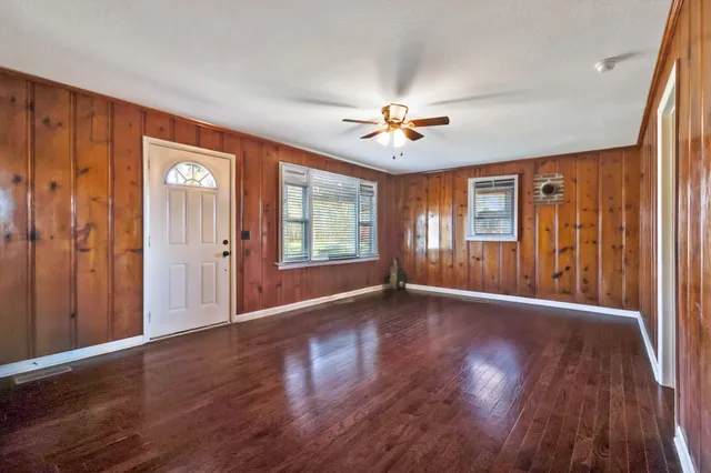 a view of an empty room with window and wooden floor