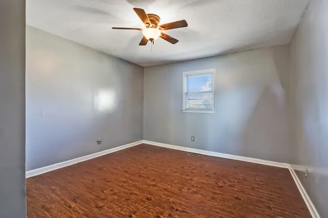 an empty room with a window and a fan