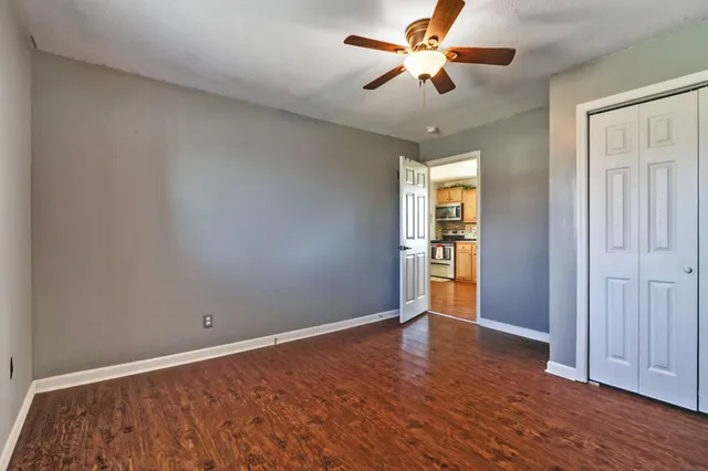 an empty room with wooden floor chandelier fan and windows