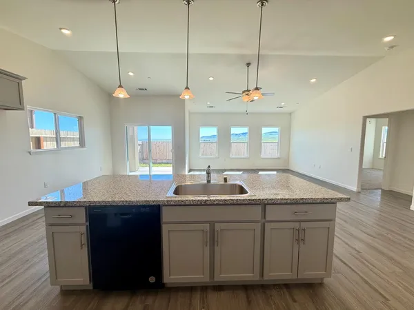 a kitchen with kitchen island granite countertop a sink a counter space appliances and a cabinets
