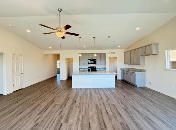 a large kitchen with kitchen island a stove a sink dishwasher a refrigerator and white countertops with wooden floor