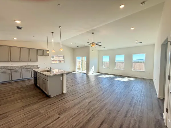 a large kitchen with a large counter top a sink stainless steel appliances and cabinets