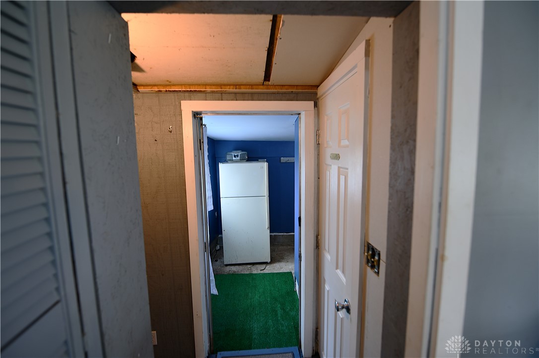 5445 Behm Road, Unit 15 Celina, OH 45822 - Photo 27 of 49 This interior hallway leads to a room featuring a refrigerator and a vibrant green rug.