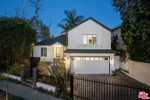 a view of a house with a small yard plants and large tree