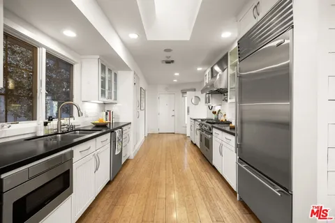 a large kitchen with stainless steel appliances granite countertop lots of counter top space and wooden floor