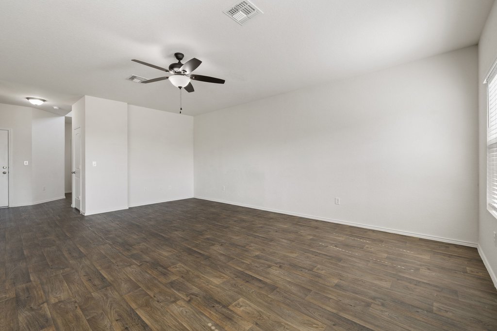 15011 Tuff Rd Manor Manor, TX 78653 - Photo 16 of 37 Open living room with a ceiling fan, generous wall space for furniture and a TV, and a hallway leading to the front entry.