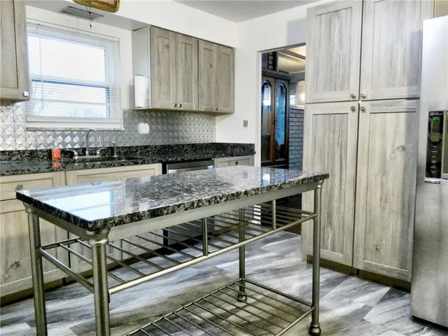 a kitchen with granite countertop a stove a sink and a refrigerator