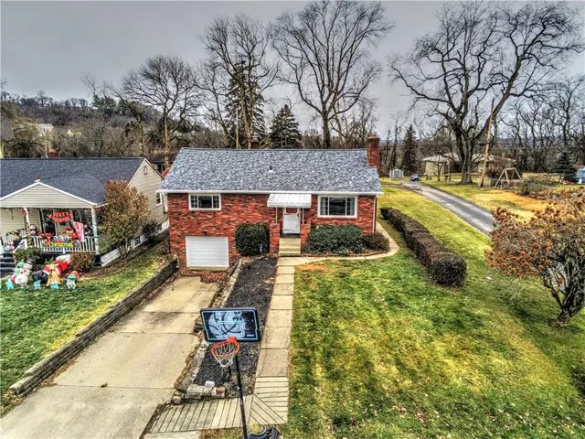a front view of house with yard and trees around